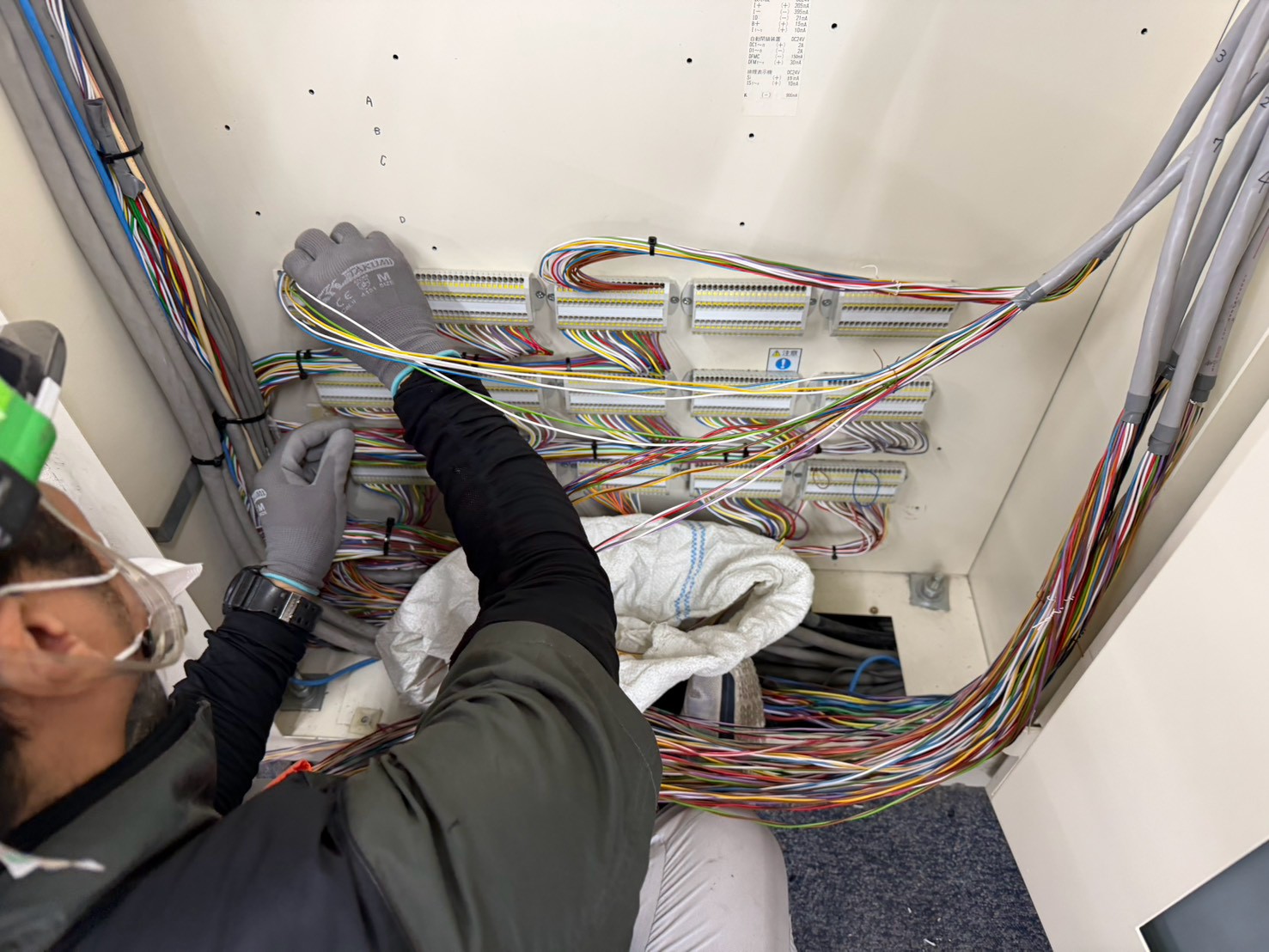 火災受信機の取り替え工事で端子まわりの配線を確認する作業